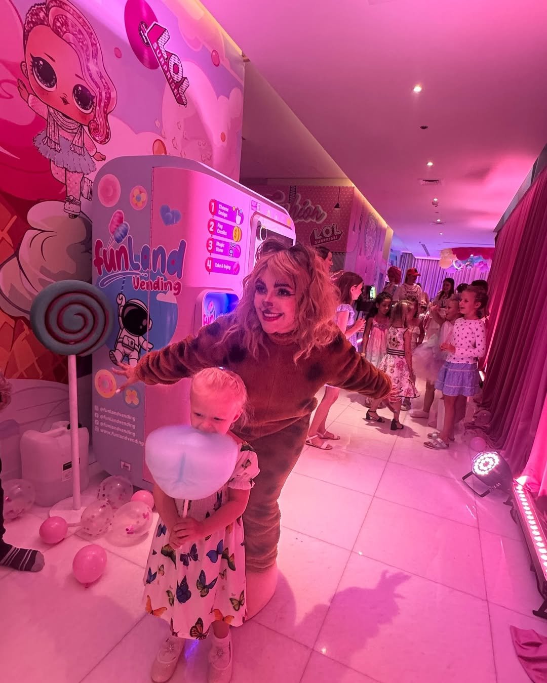 Child enjoying fresh cotton candy beside the Funland Vending machine at an LOL Surprise themed birthday party in Dubai